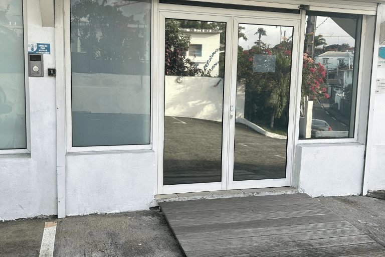Entrée vitrée du cabinet Kiné'sens équipée d'une rampe d'accès PMR et d'un interphone sécurisé